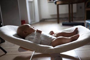 Bébé éveillé allongé dans un transat en tissu posé au sol du salon